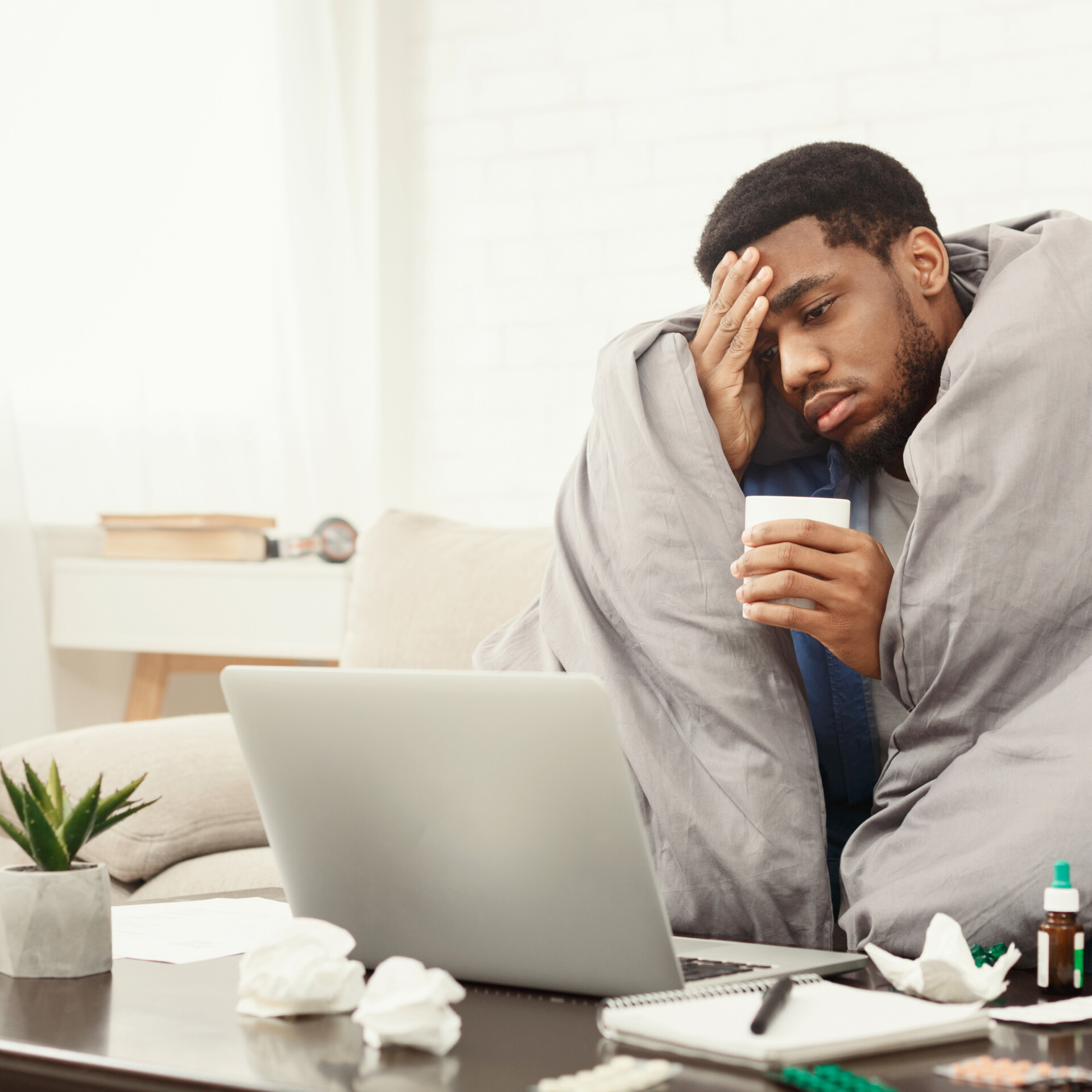 Sick african-american man working on laptop at home Acute Conditions<br />
Colds and flu<br />
Fevers<br />
Minor injuries<br />
Food poisoning<br />
Allergic reactions